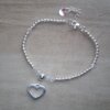 PULSERA DE ACERO BLANCO  BOLITAS Y MOSTACILLAS CRISTAL CON DIJE CORAZON CALADO. LARGO 17 + 3 CM
