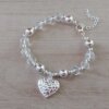 PULSERA DE ACERO BLANCO MOSTACILLAS TRANSPARENTES Y BOLITAS CON DIJE CORAZÓN. LARGO 17 + 3.5 CM EXT.
