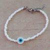 PULSERA DE TANZA CON MOSTACILLAS BLANCA Y OJO TURCO CON TERMINAL DE ACERO. LARGO 18 + 3 CM EXT.