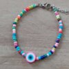 PULSERA DE TANZA CON MOSTACILLAS MULTICOLOR Y OJO TURCO FUCSIA CON TERMINAL DE ACERO. LARGO 18 + 3 CM EXT.