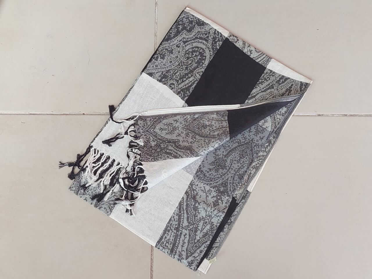 PASHMINA TRAMADA CON FLECOS Y CUADRANTES EN TONOS BLANCO, GRIS Y NEGRO. 70 X 180 CM.