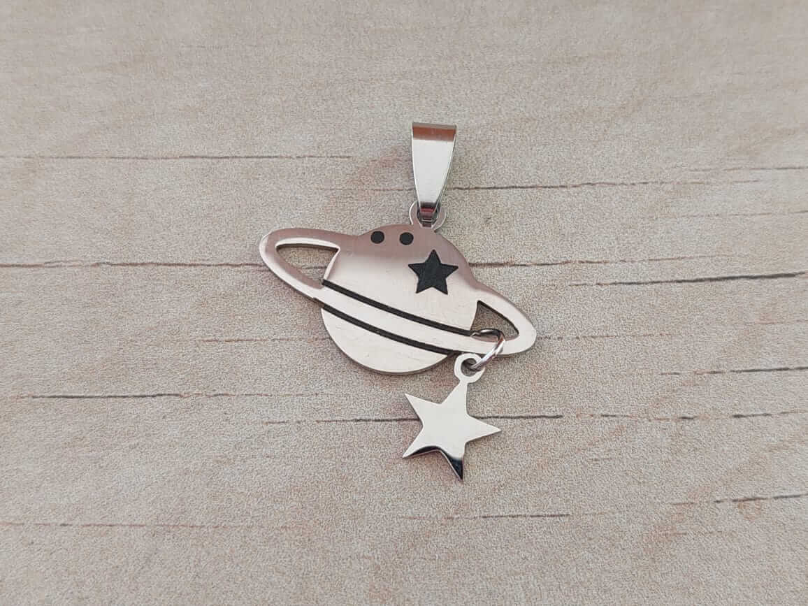 DIJE DE ACERO SATURNO CON ESTRELLA COLGANTE. 29 X 25 MM