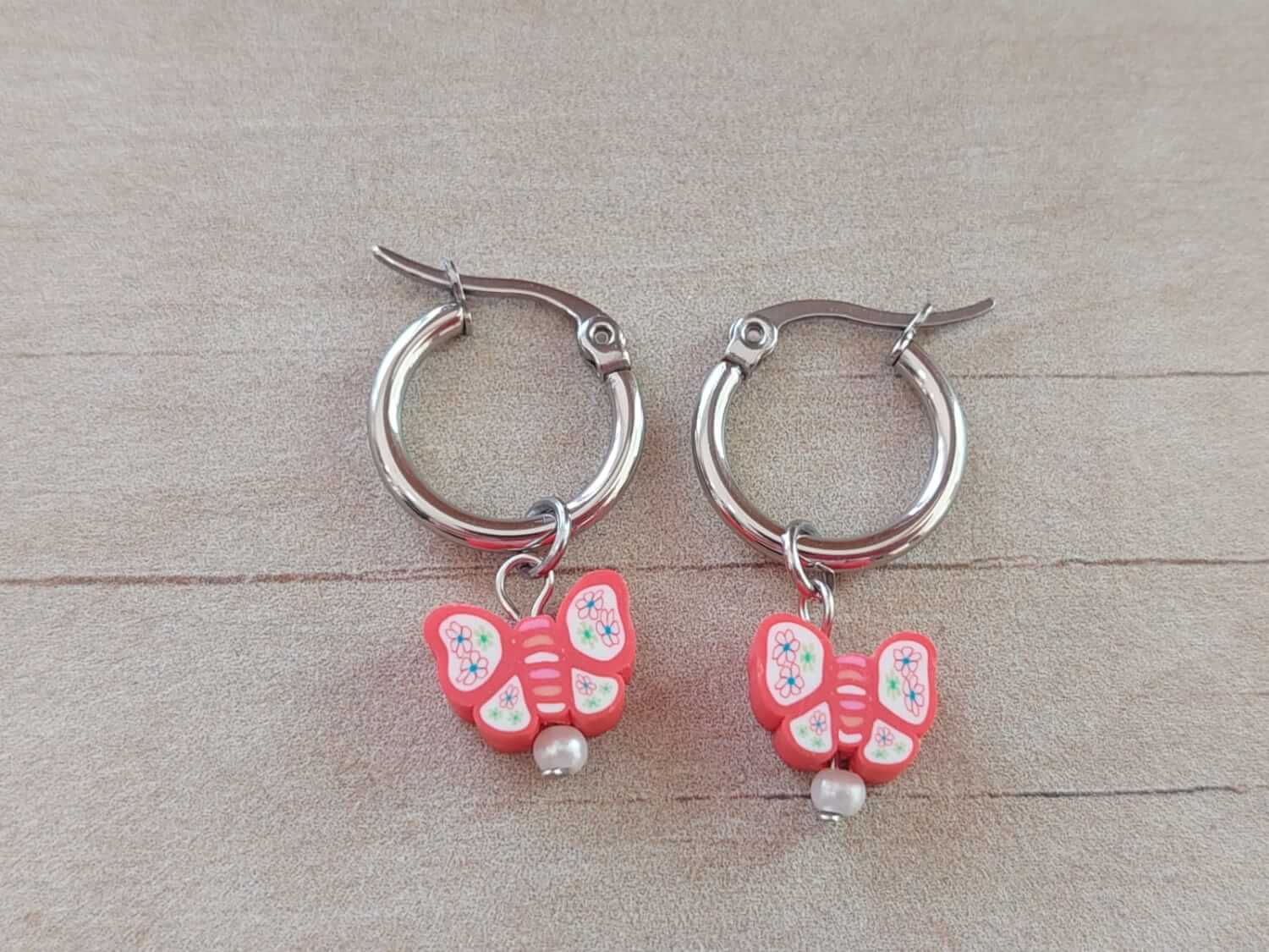 ARO DE ACERO ARGOLLA 14 MM CON DIJE MARIPOSA CORAL COLGANTE