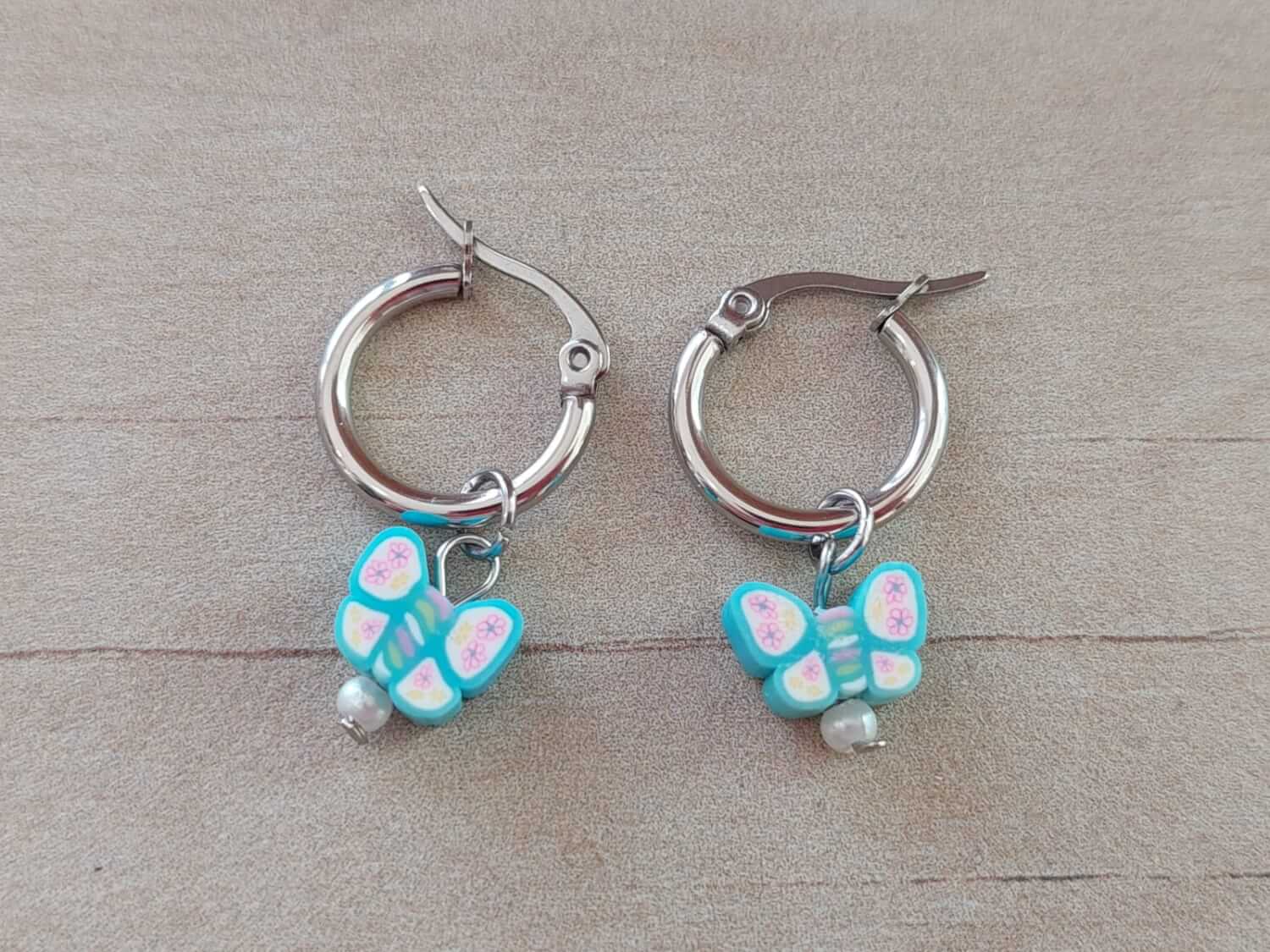 ARO DE ACERO ARGOLLA 14 MM CON DIJE MARIPOSA CELESTE COLGANTE