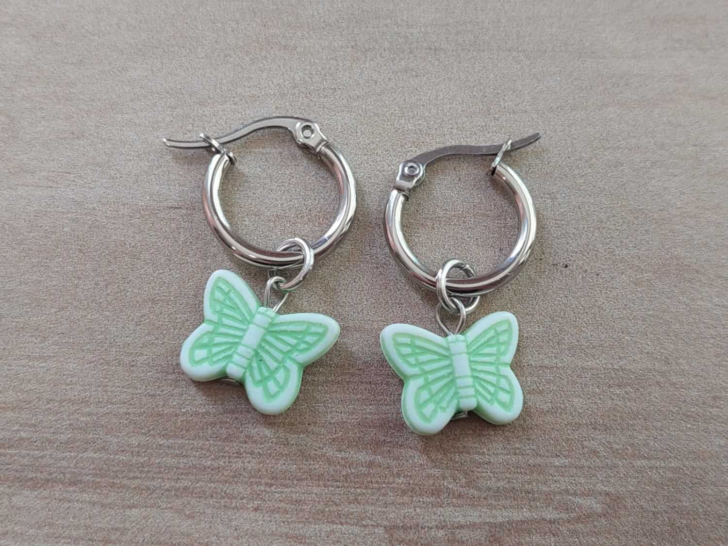 ARO DE ACERO ARGOLLA 14 MM CON DIJE MARIPOSA VERDE COLGANTE. LARGO TOTAL 30 MM.