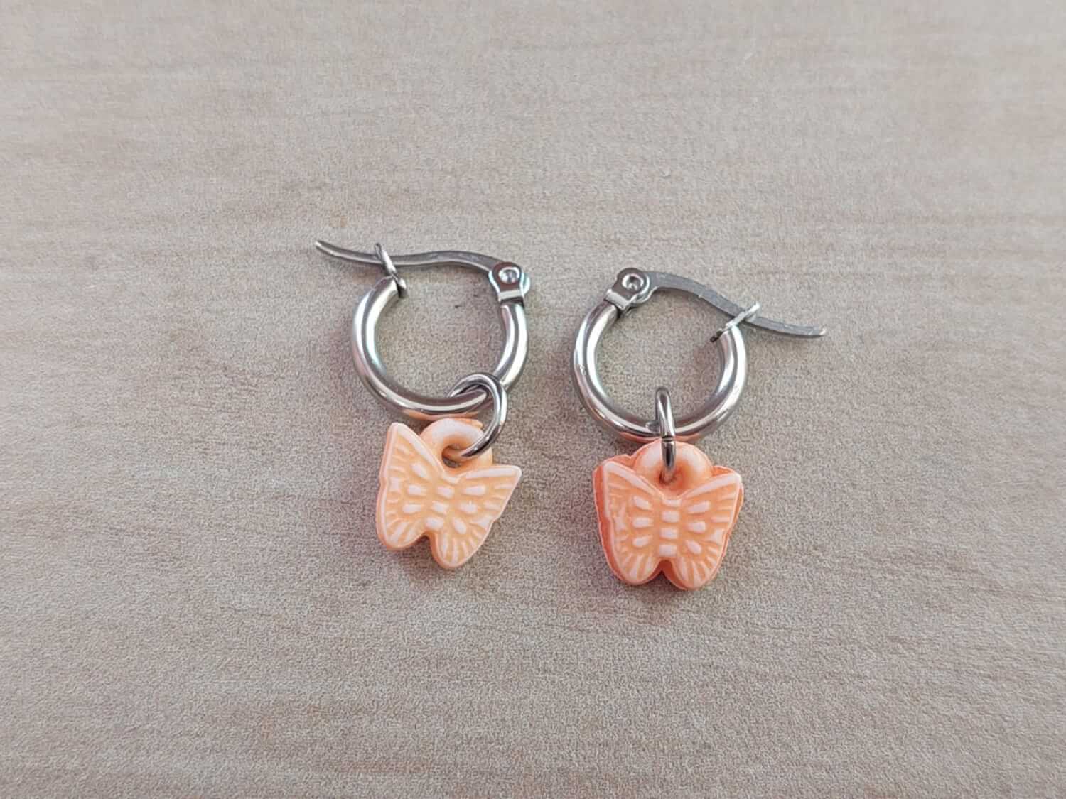 ARO DE ACERO ARGOLLA 12 MM CON MARIPOSA COLGANTE DE ACRÍLICO COLOR NARANJA