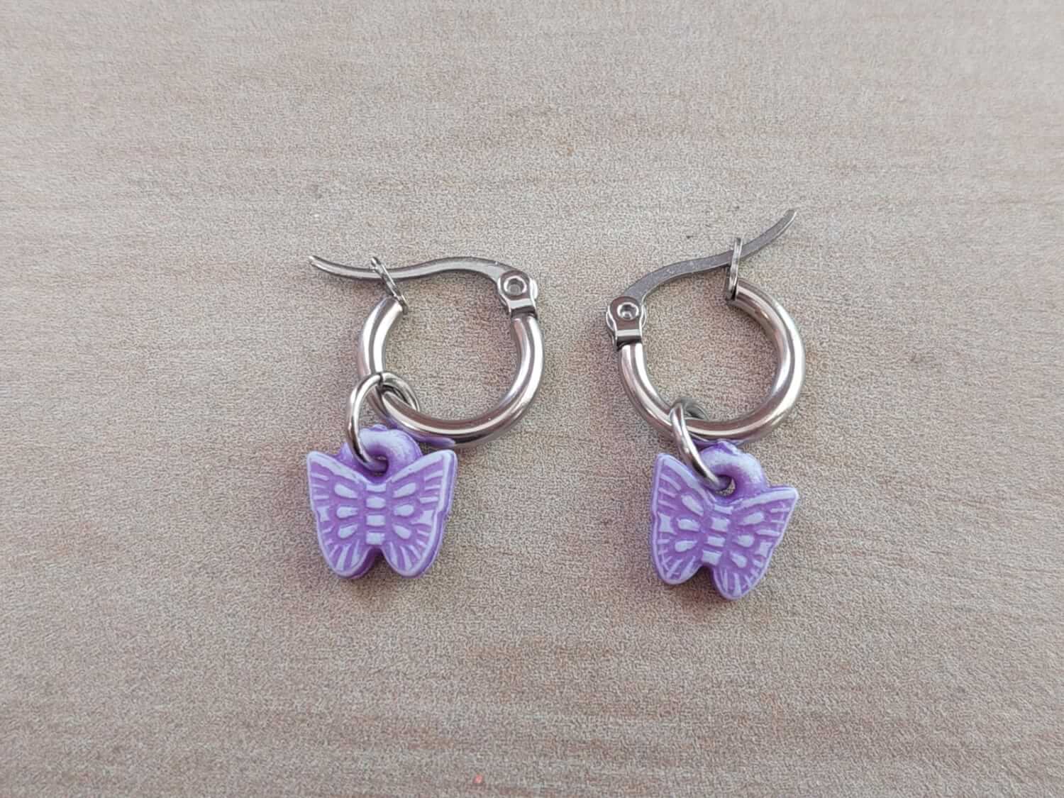 ARO DE ACERO ARGOLLA 12 MM CON MARIPOSA COLGANTE DE ACRÍLICO COLOR LILA