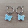 ARO DE ACERO ARGOLLA 14 MM CON DIJE MARIPOSA CELESTE COLGANTE. LARGO TOTAL 30 MM.