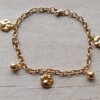 PULSERA DE ACERO DORADO ESLABÓN TIFFANY CON BOLITAS Y DIJES DE HUELLITAS COLGANTES. LARGO 19,5 CM