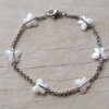 PULSERA DE ACERO ROLO 2.0 CON MARIPOSAS DE ACRÍLICO BLANCO NACARADO ENGARZADA. LARGO 18.5 CM