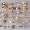 ANILLOS DE ACERO DORADO FORMAS CALADAS X 36 UNIDADES SURTIDOS EN MEDIDAS. (MEDIDAS DEL 16 AL 19)