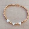 PULSERA DE ACERO DORADO BOLITAS 3 MM CON TRES CORAZONES DE NÁCAR EN EL CENTRO. LARGO 18 CM.