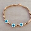 PULSERA DE ACERO DORADO BOLITAS 3 MM CON TRES OJITOS TURCOS DE NÁCAR EN EL CENTRO. LARGO 18 CM.