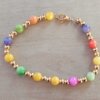 PULSERA DE ACERO DORADO DOS BOLITAS 3 MM INTERCALADAS CON BOLITAS DE NÁCAR MULTICOLOR. LARGO 18 CM.