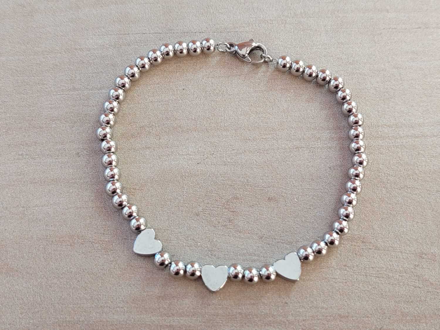 PULSERA DE ACERO DE BOLITAS 3 MM CON TRES CORAZONES PULIDOS EN EL CENTRO. LARGO 18 CM.
