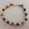 PULSERA DE ACERO DORADO DOS BOLITAS 3 MM INTERCALADAS CON BOLITAS OJO DE TIGRE. LARGO 18 CM.