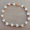 PULSERA DE ACERO DORADO DOS BOLITAS 3 MM INTERCALADAS CON CORAZÓN NÁCAR BLANCO. LARGO 18 CM.