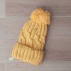 GORRO TEJIDO CON PIEL EN SU INTERIOR COLOR AMARILLO CON POMPÓN DE PIEL.