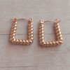 ARO DE ACERO DORADO ARGOLLA HUECA CON FORMA DE TRAPECIO RETORCIDO. TAMAÑO 20 X 18 MM