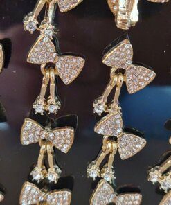 BLISTER DE AROS PASANTE DE ACERO DORADO MOÑO CON STRASS Y STRASS COLGANTES. X 12 PARES.