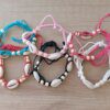 PULSERA HILO AJUSTABLE COLORES SURTIDOS CON CARACOLES Y SEMILLAS ENHEBRADAS. PACK X 12 UNIDADES SURTIDAS.