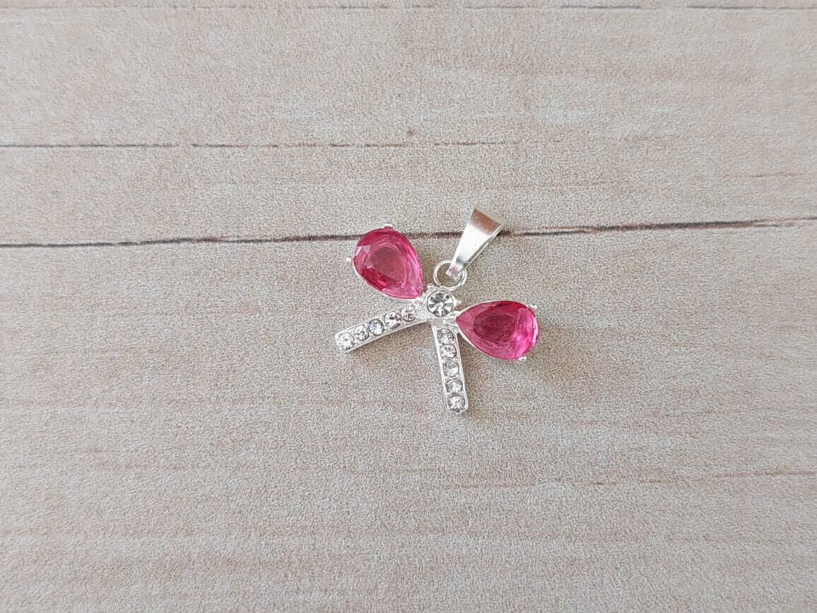 DIJE DE ACERO BLANCO MOÑO CON CUBIK FUCSIA. 17 X 10 MM
