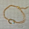 PULSERA DE ACERO DORADO ESLABÓN ESPEJITO DOBLE CON CENTRO CORAZÓN CALADO CON OJO BLANCO. LARGO 17,5 + 3 CM EXT.