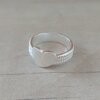 ANILLO DE ACERO BLANCO CINTA LABRADO CON CORAZÓN CENTRAL.