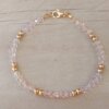 PULSERA DE TANZA CON MOSTACILLAS ROSAS, DOS BOLITAS 3 MM INTERCALADAS Y TERMINAL DE ACERO DORADO. LARGO 18,5 CM.