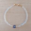 PULSERA DE TANZA CON MOSTACILLAS CRISTAL, OJO TURCO CENTRAL Y TERMINAL DE ACERO DORADO. LARGO 18,5 CM.