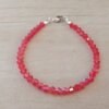 PULSERA DE TANZA CON MOSTACILLAS ROJO Y TERMINAL DE ACERO BLANCO. LARGO 18 CM.