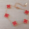 PULSERA DE ACERO DORADO ESLABÓN ESPEJITO CON DIJE VAN CLEEF ACRÍLICO ROJO. LARGO 17,5 + 6 CM EXT.