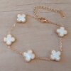 PULSERA DE ACERO DORADO ESLABÓN ESPEJITO CON DIJE VAN CLEEF ACRÍLICO BLANCO. LARGO 17,5 + 6 CM EXT.