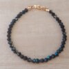 PULSERA DE TANZA CON MOSTACILLAS NEGRAS Y TERMINAL DE ACERO DORADO. LARGO 18 CM.