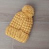 GORRO TEJIDO CON PIEL EN SU INTERIOR COLOR MAÍZ CON POMPÓN DE PIEL.
