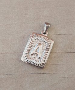 DIJE DE ACERO INICIAL. TAMAÑO APROXIMADO 15 X 20 MM