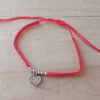 PULSERA DE HILO ROJO AJUSTABLE CON BOLITAS Y DIJE DE ACERO CORAZÓN CON STRASS.