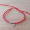 PULSERA DE HILO ROJO AJUSTABLE CON BOLITAS Y DIJE DE ACERO FLOR CON STRASS.