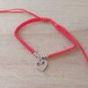 PULSERA DE HILO ROJO AJUSTABLE CON BOLITAS Y DIJE DE ACERO CORAZÓN CALADO CON STRASS.