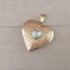 DIJE DE ACERO DORADO RELICARIO CORAZÓN TRABAJADO CON ACRÍLICO TORNASOL EN EL CENTRO. TAMAÑO 28 MM