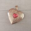 DIJE DE ACERO DORADO RELICARIO CORAZÓN TRABAJADO CON ACRÍLICO ROJO EN EL CENTRO. TAMAÑO 28 MM