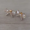 Aro de acero dorado pasante en forma de moño con cubik y strass