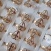 ANILLOS DE ACERO DORADO FIGURA CALADA CORAZÓN CON CRUZ X 36 UNIDADES. (MEDIDAS DEL 16 AL 20)
