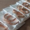 BLISTER DE ARGOLLAS ACERO ROSE TRABAJADAS CON TACHAS X 12 PARES. DIÁMETROS 12/18/23 MM (4 PARES DE CADA MEDIDA)