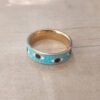 ANILLO CINTA DE ACERO DORADO ESMALTADO CELESTE CON OJITOS