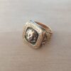 ANILLO DE ACERO DORADO ESTILO SELLO CON CABEZA DE LEON Y PATRON GRIEGO
