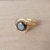 ANILLO DE ACERO DORADO CON STRASS NEGRO REDONDO Y STRASS BLANCO ENVOLVENTE
