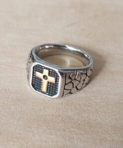 ANILLO DE ACERO ESTILO SELLO CON CRUZ DORADA Y DETALLES EN NEGRO.