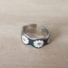 ANILLO ALIANZA DE ACERO IRREGULAR, ABIERTO Y ESMALTADO EN NEGRO CON MARGARITAS