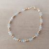 PULSERA DE TANZA CON DOS MOSTACILLAS BLANCAS Y DOS BOLITAS 3 MM INTERCALADAS. TERMINAL DE ACERO DORADO. LARGO 18,5 CM.